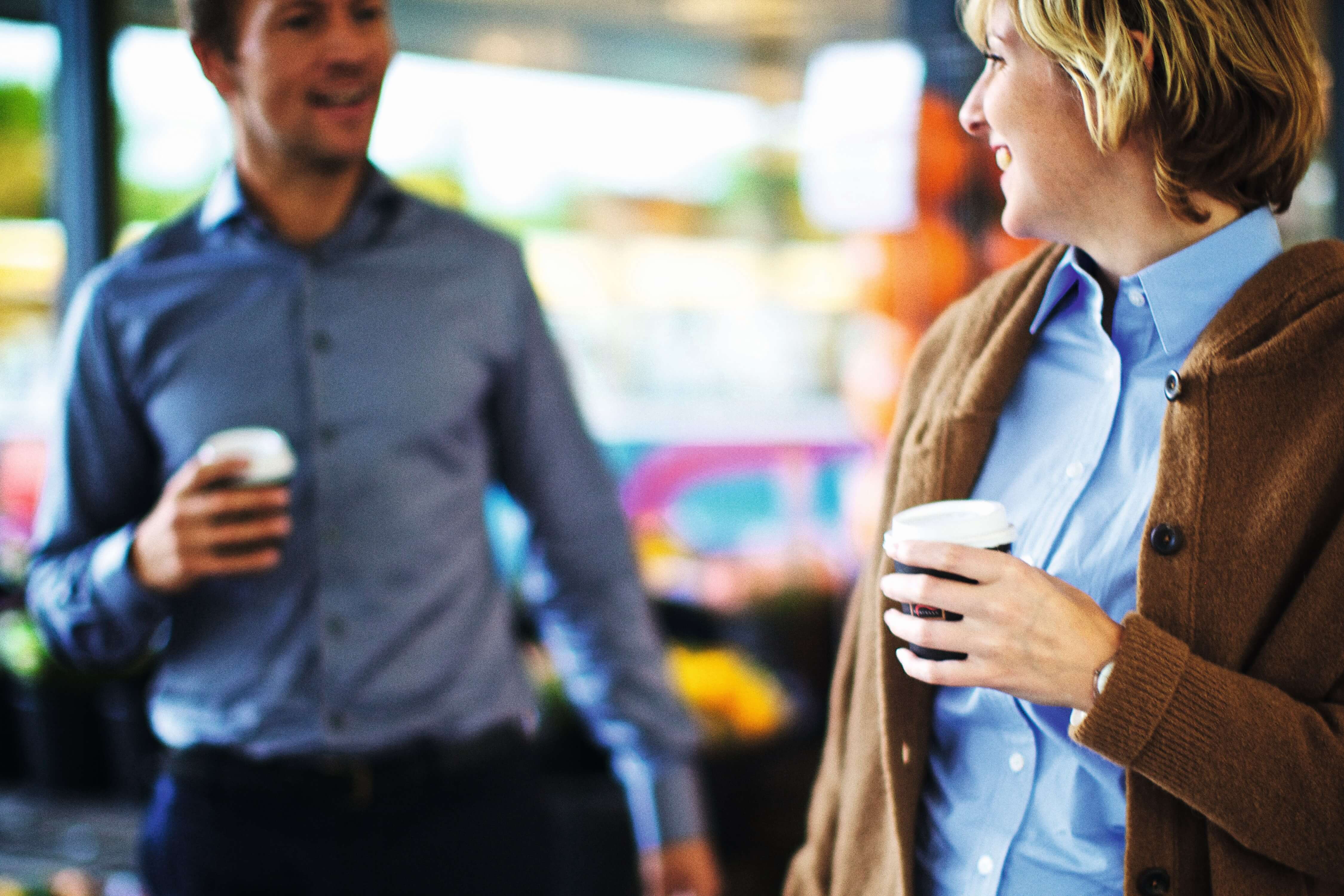 Woman and Man walking,talking with a cup of coffee to go in hand